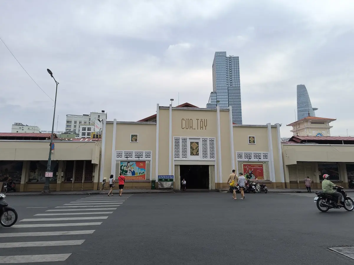 Cổng phía tây chợ Bến Thành với các tòa nhà hiện đại phía sau
