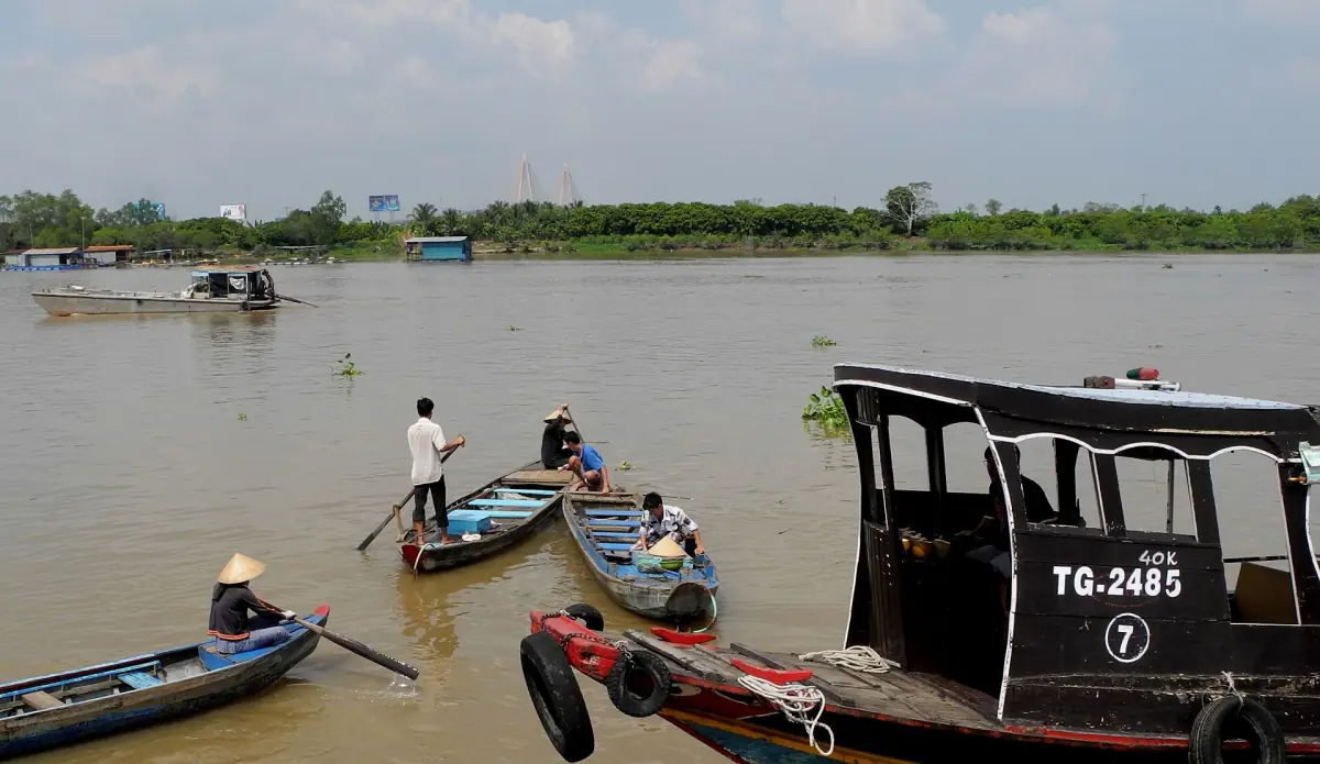 Small boats and a ferry at a pier on the Mekong River
