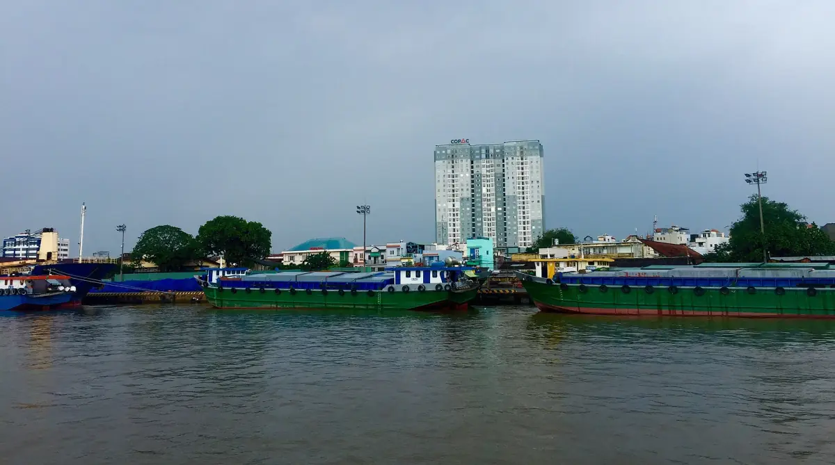Frachtkähne am Ufer des Saigon-Flusses mit Wohntürmen dahinter