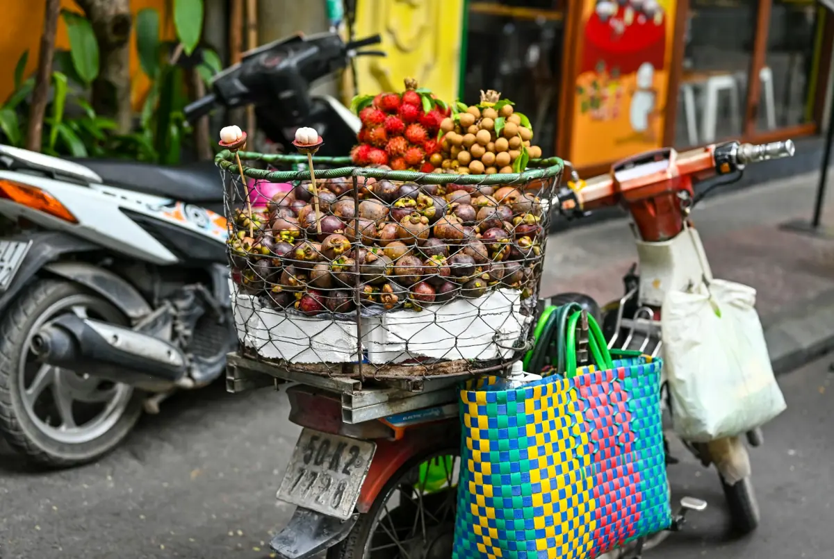 Scooter carrying a basket of mangosteen and rambutan